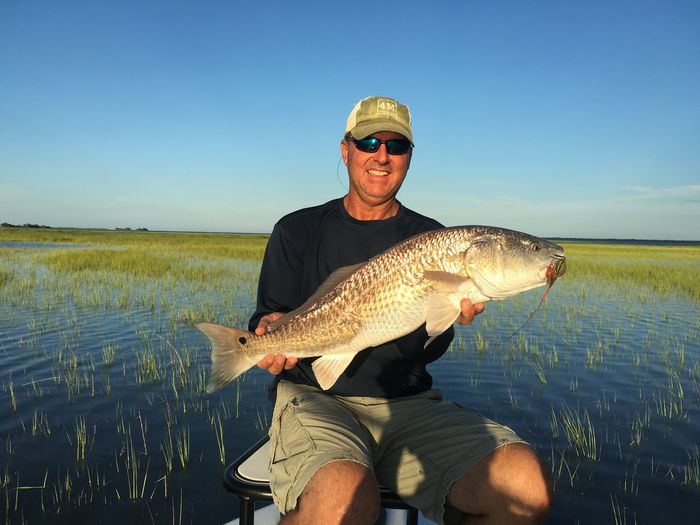 Angler holding a redfish in the marsh